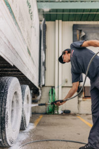 Pressure washing the dirt and salt off of the tires of a semi-truck.